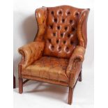 A George III style mahogany framed wingback open armchair, upholstered in tan buttonback studded