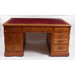 A circa 1900 faded walnut twin pedestal partners desk, having a gilt tooled leather inset writing
