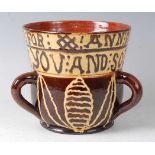 A Wrotham style brown and yellow slipware tyg, the frieze bearing motto 'THIS CUP I MADE FOR ANN