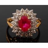 A yellow metal, ruby and diamond oval cluster ring, featuring an oval faceted ruby within two