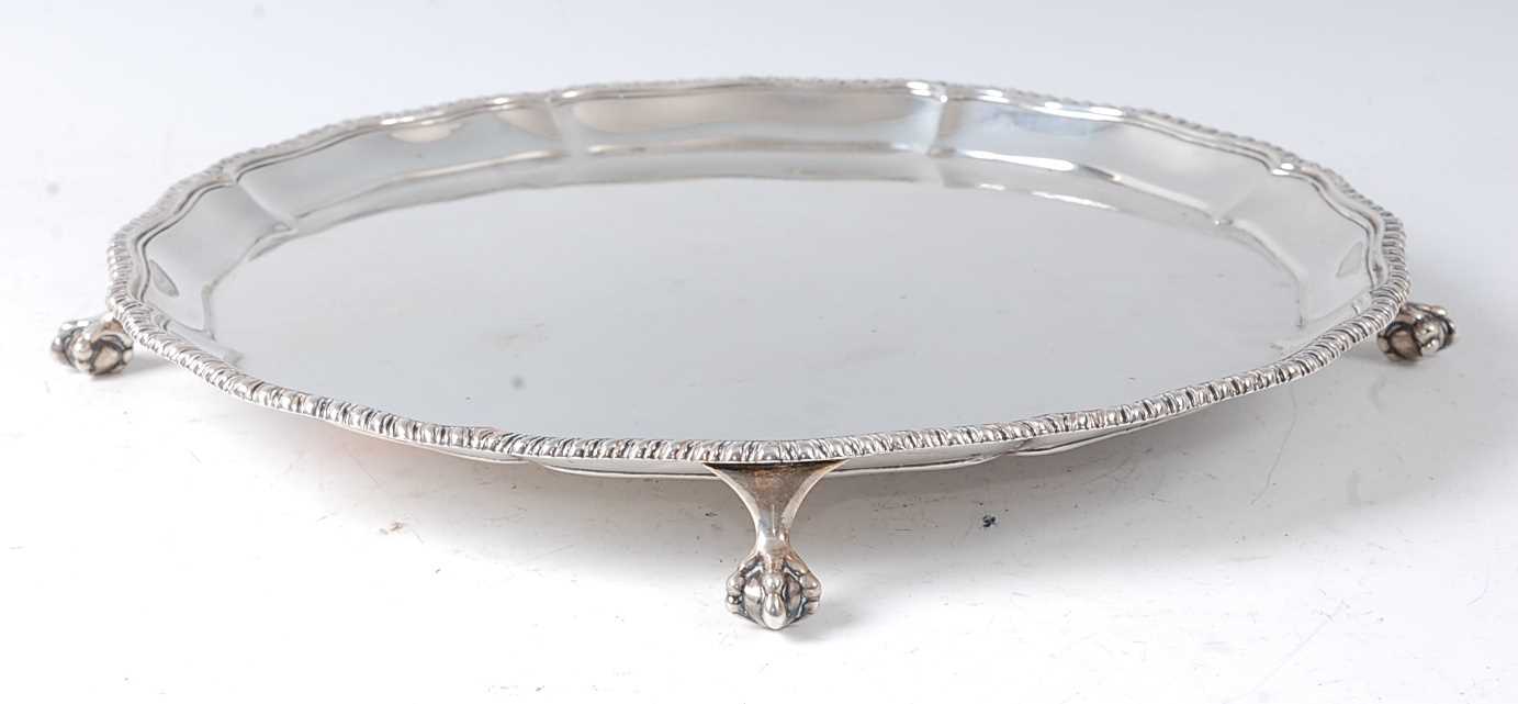 A late Victorian silver salver, having a gadrooned piecrust rim, raised on three claw and ball feet,