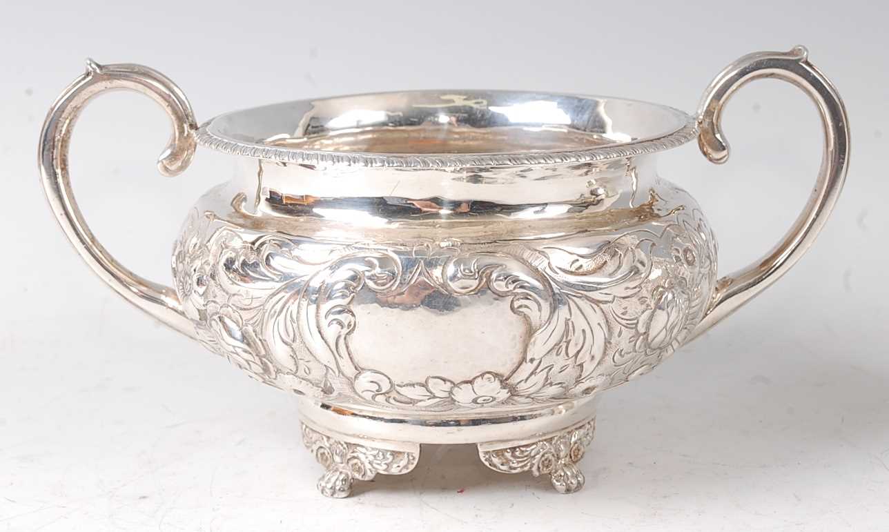 A George III silver twin handled sugar bowl, of squat circular form, having floral repousee