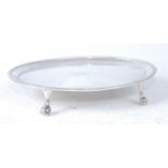 A George III silver teapot stand. of beaded oval form, having engraved monogram, all raised on