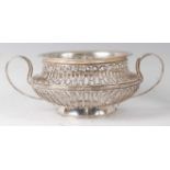 A George V pierced silver bowl, of squat circular form, having twin applied leaf capped handles,