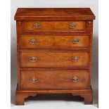 A George I style walnut bachelors chest, the oak crossbanded and feather strung fold-over top