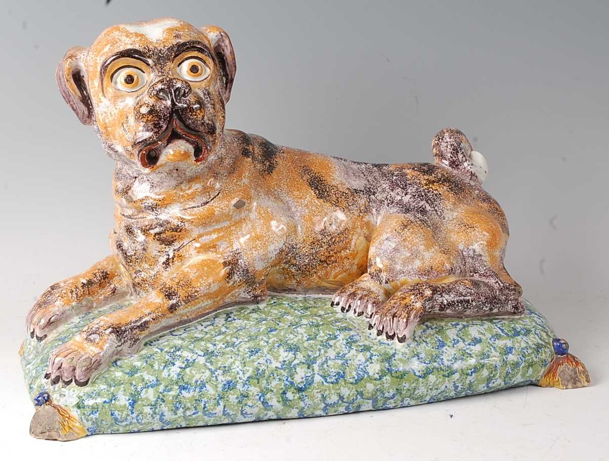 A French faience model of a recumbent pug dog upon a cushion, having all-over sponged decoration (