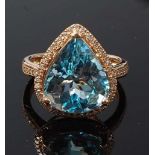 A yellow metal, topaz and diamond pear shaped cluster ring, featuring a centre pear cut blue topaz