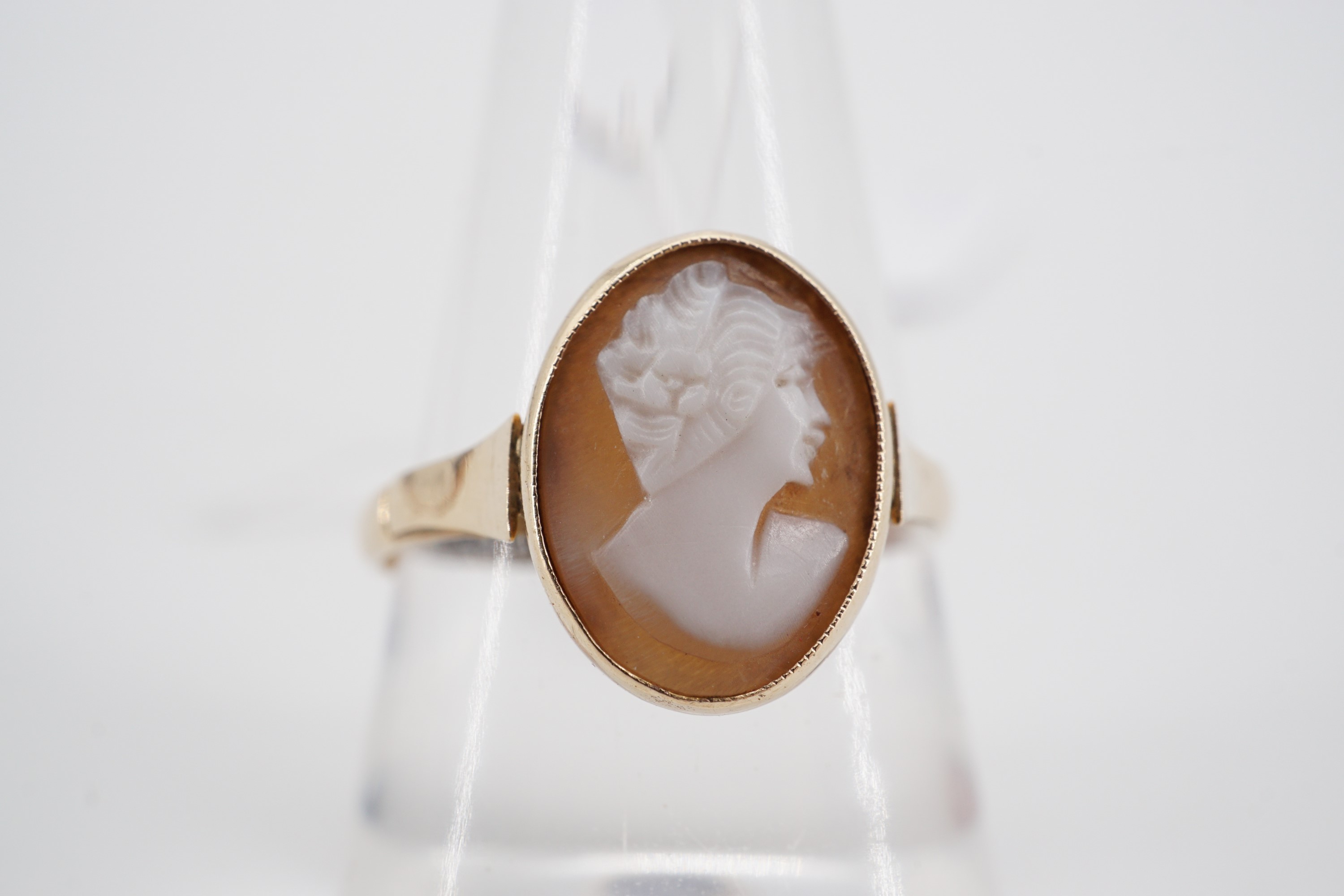 An antique carved shell cameo ring depicting the profile of a fashionable young lady, millegrain and