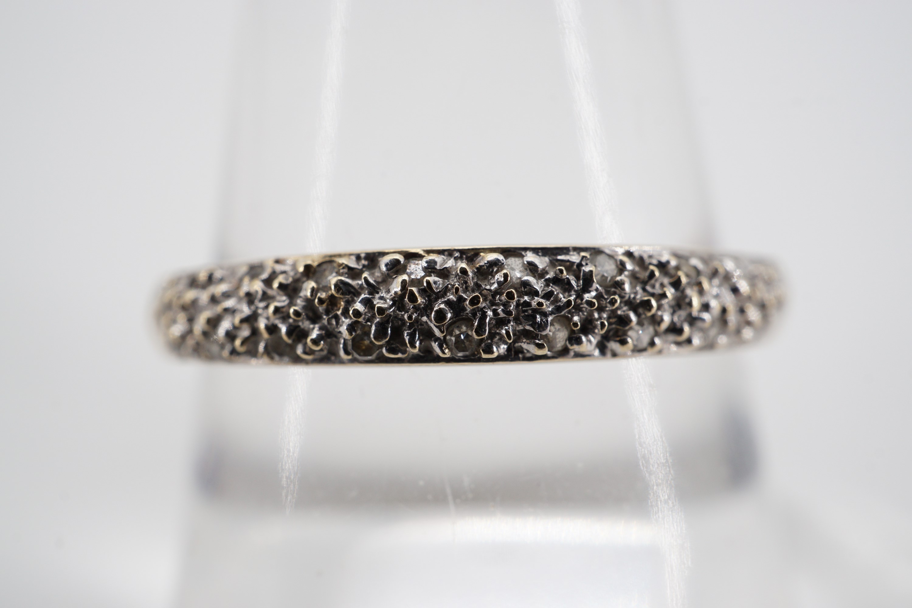 A contemporary 9ct gold and diamond frosted eternity ring, the face being pellet and illusion-set