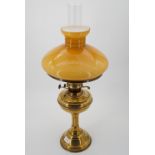 A brass oil lamp and amber shade, 63 cm high