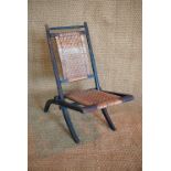 A Victorian ebonised folding chair with caned seat and back