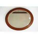A George V mahogany-framed oval wall mirror, with bevel-edged plate, 59 cm x 49 cm