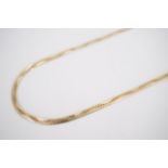 A yellow metal snake link neck chain with undulating spirally engraved decoration, tested as gold,