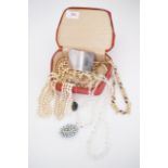 A vintage red travel jewellery case containing costume necklaces, including faux pearls and paste,