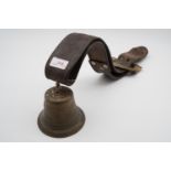 An antique brass cow bell and strap