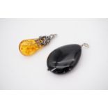 A modern sun-spangled amber and white metal pendant drop, and a polished onyx pendant, both