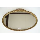 A gilt framed oval wall mirror with bow surmount, mid 20th Century, 46 x 73 cm