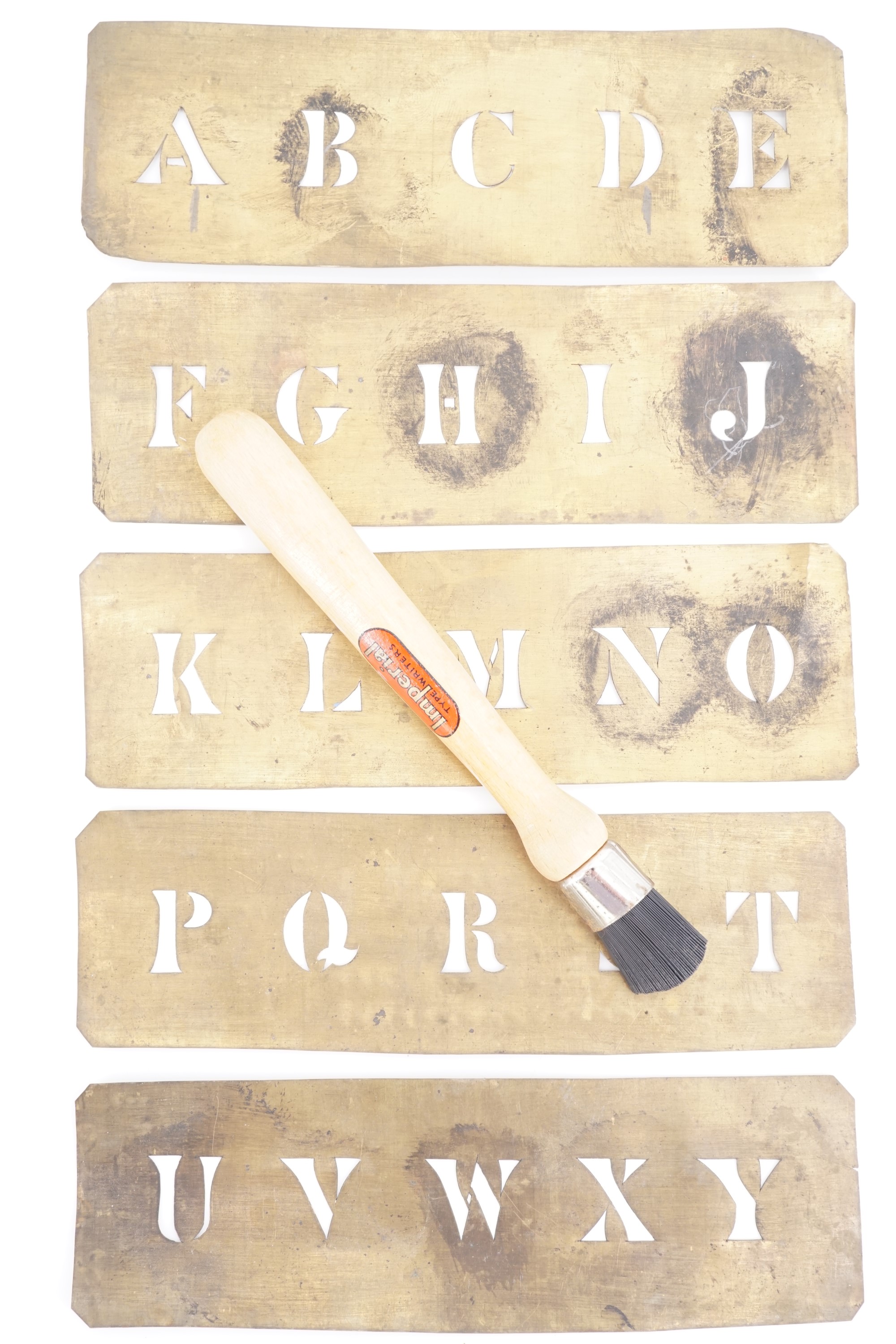 Antique brass alphabet stencils together with a brush