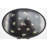 A hand-decorated black lacquered oval wooden tea tray, painted in a pattern of floral sprigs, signed