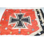 Part of a Second World War German military flag bearing a large collecting of Nazi rally badges