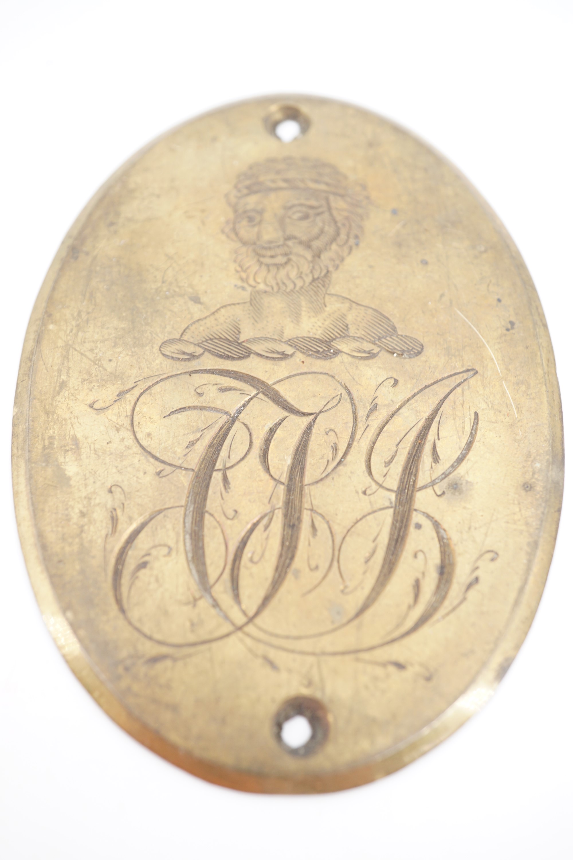 An early 19th Century engraved brass plaque incorporating an armorial crest and monogram, 8 cm x 6