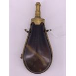 An early 19th Century brass-mounted polished horn gunpowder flask, having a patent sprung push-