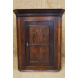 An 18th Century oak corner cabinet, the door faced by half-round bead mouldings framing cross-cut