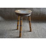 A small turned wooden three legged stool, 26 cm x 38 cm