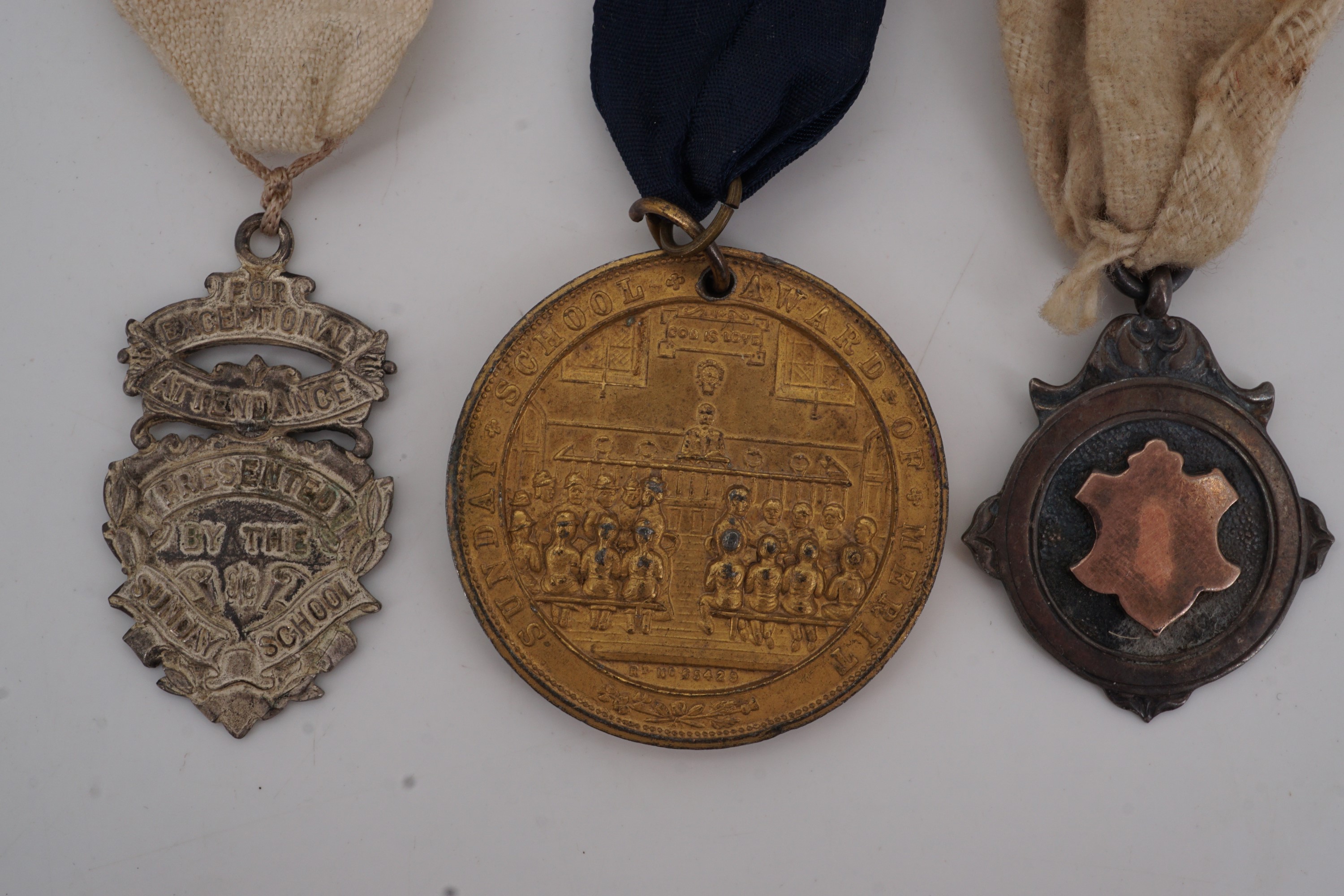 An early 20th Century silver watch chain fob medallion together with two Sunday school attendance