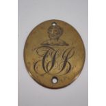 An early 19th Century engraved brass plaque incorporating an armorial crest and monogram, 8 cm x 6