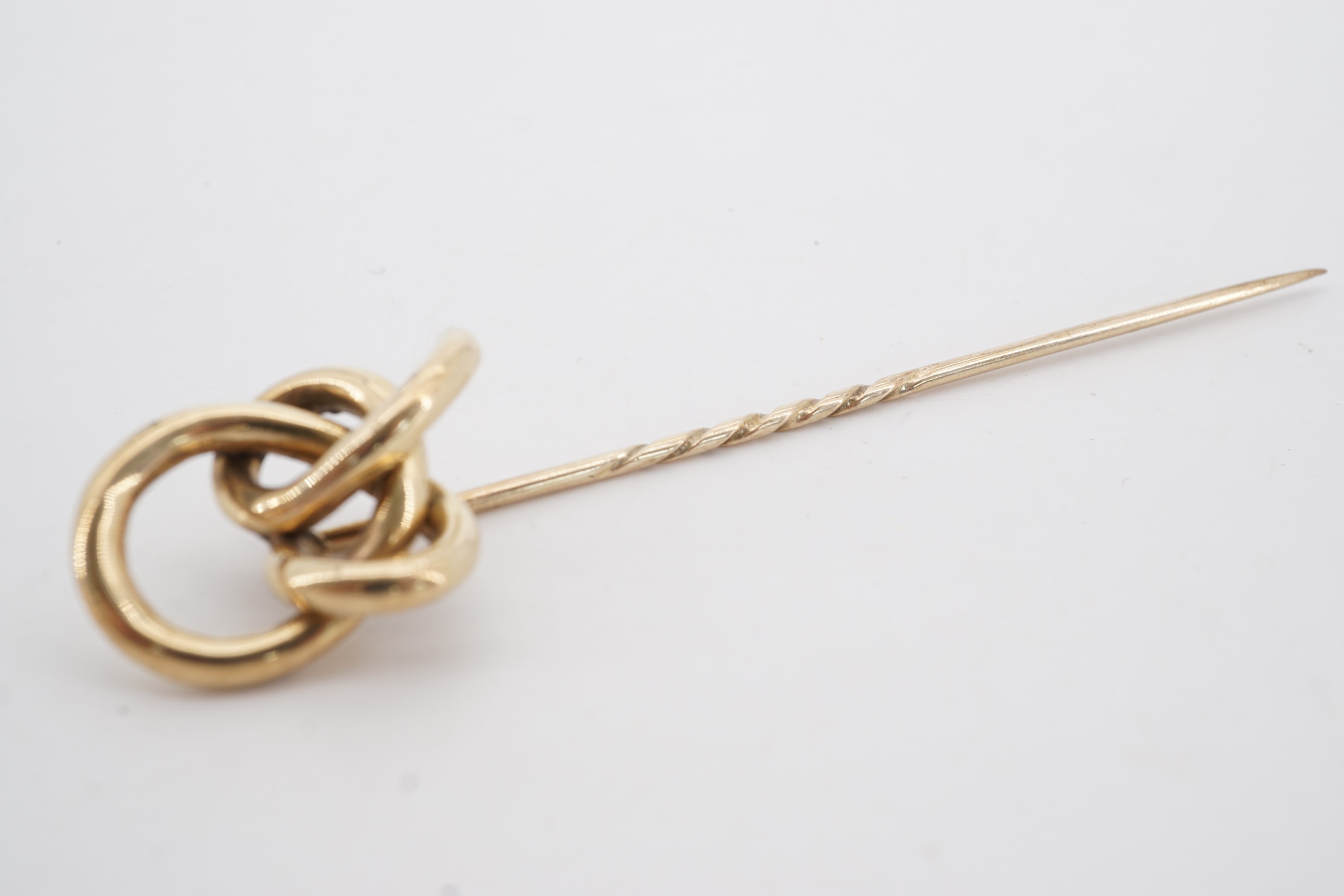 A Victorian yellow metal stick pin, its terminal in the form of an open knot, 9.5 cm, 6.2 g