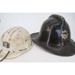 A vintage fireman's helmet together with a miner's hard hat