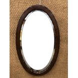 A mahogany-framed oval wall mirror