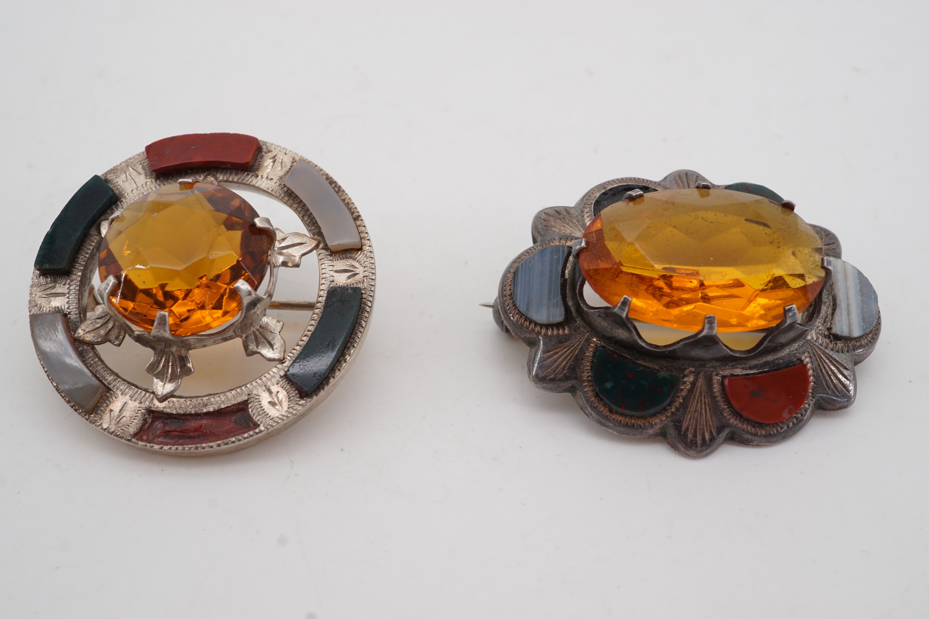 Two antique Scottish white metal and polished hard stone brooches, each centred by a facet-cut