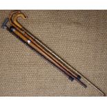 A walking cane, a shepherd's crook, a silver-collared walking cane and one other