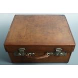 An Edwardian tan hide travelling case fitted for and containing silver-mounted cut glass toiletry