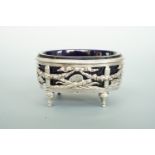 A French Neoclassical style silver salt cellar with blue glass liner, reticulated in depiction of