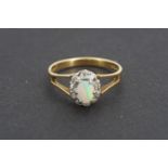 A lady's 18ct gold opal and diamond flower head cluster ring, the opal of approximately 6 x 4 mm,