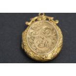 An early 20th Century 9 ct gold pendant locket, foliate-scroll-engraved and having an adorsed scroll