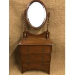A 1920s oak dressing chest of diminutive stature, the oval mirror raised on twist turned supports,