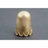 A Victorian yellow metal thimble, with cusped rim and foliate engraved decoration, tested as gold,