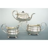A George IV silver three piece tea service, having reeded decoration, scroll handles, and ball feet,