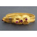 A Victorian woven gilt metal flexible bracelet faced by a ribbon bow set with amethyst coloured