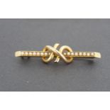 A late 19th / early 20th Century pearl-set yellow metal brooch, the pearls set within a knot-