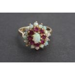 A vintage opal and ruby flower head cluster cocktail ring, in a tiered arrangement with central oval