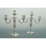 A pair of Elizabeth II silver two branch three-light candelabra, each having faceted inverted bell-
