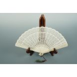 A Regency bone brise fan, with maroon and green silk and bead tassel, guard 19 cm