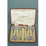 A cased set of champleve enamelled silver gilt tea spoons and sugar tongs, "foreign" mark,