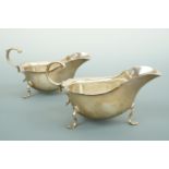 A pair of George V silver sauce boats, of helmet form, having a cusped rim flange, flying scroll