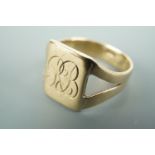 A yellow metal signet ring, having a monogram-engraved rectangular face and bifurcated shank,